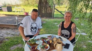 Una mesa redonda con diversos alimentos y una jarras, colocada al aire libre sobre un césped.