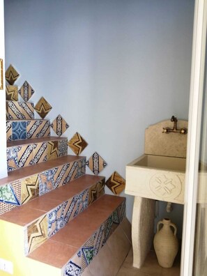 Stunning staircase with decorative tiles and a vintage sink, blending modern and classic design elements.