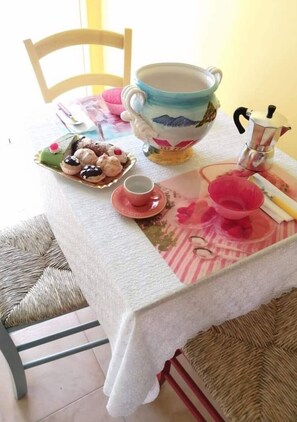Enjoy a warm breakfast at this inviting dining table, complete with a coffee pot, delicate china, and sweet treats.