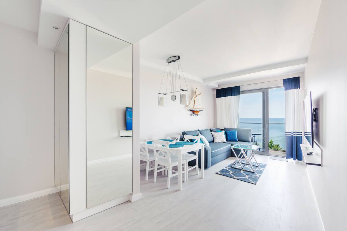 Un salon moderne comprenant un canapé, une table à manger et des chaises, un balcon avec vue et une grande fenêtre.