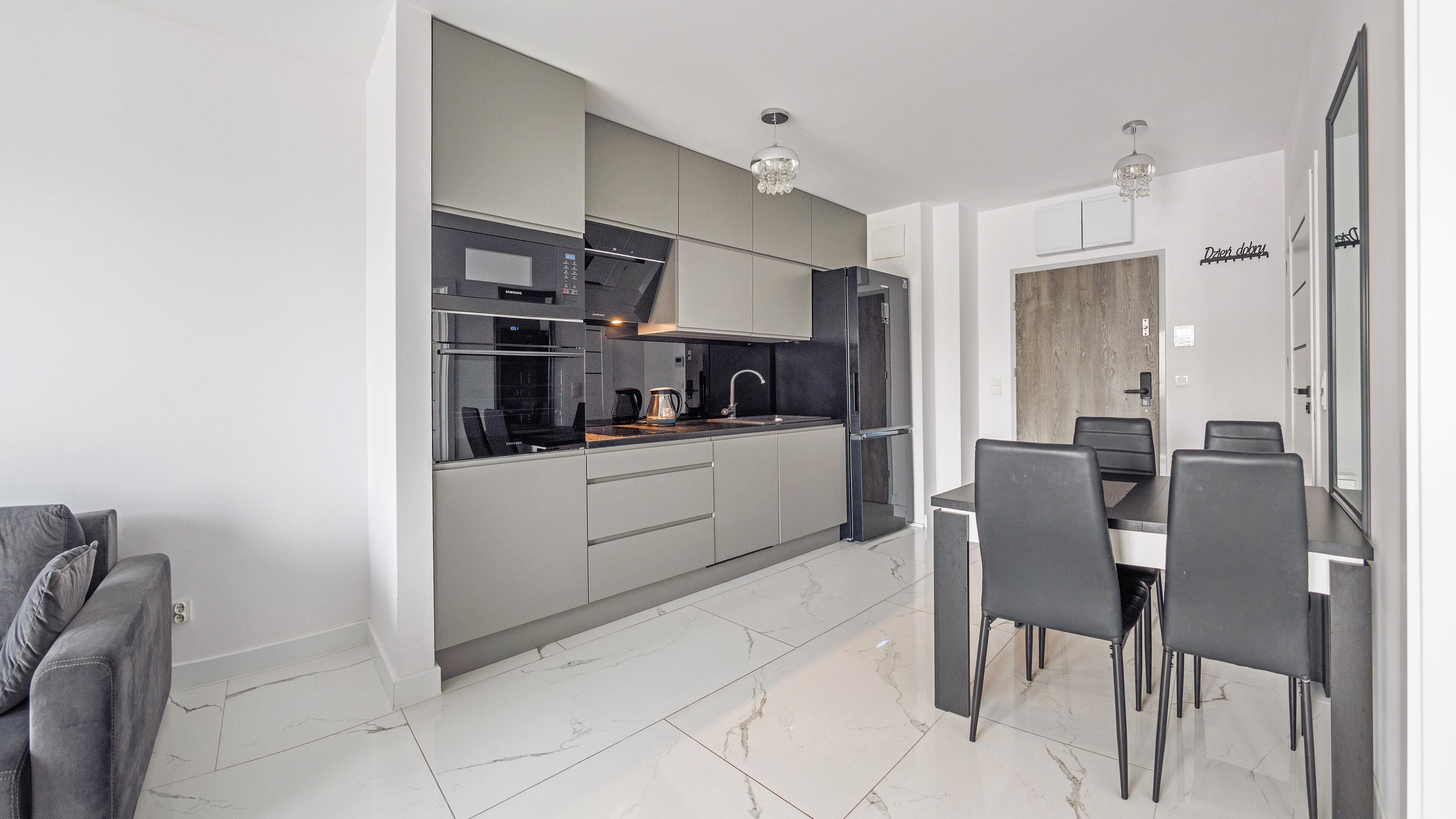 A modern kitchen with a dining area, featuring a built-in oven, microwave, and refrigerator.