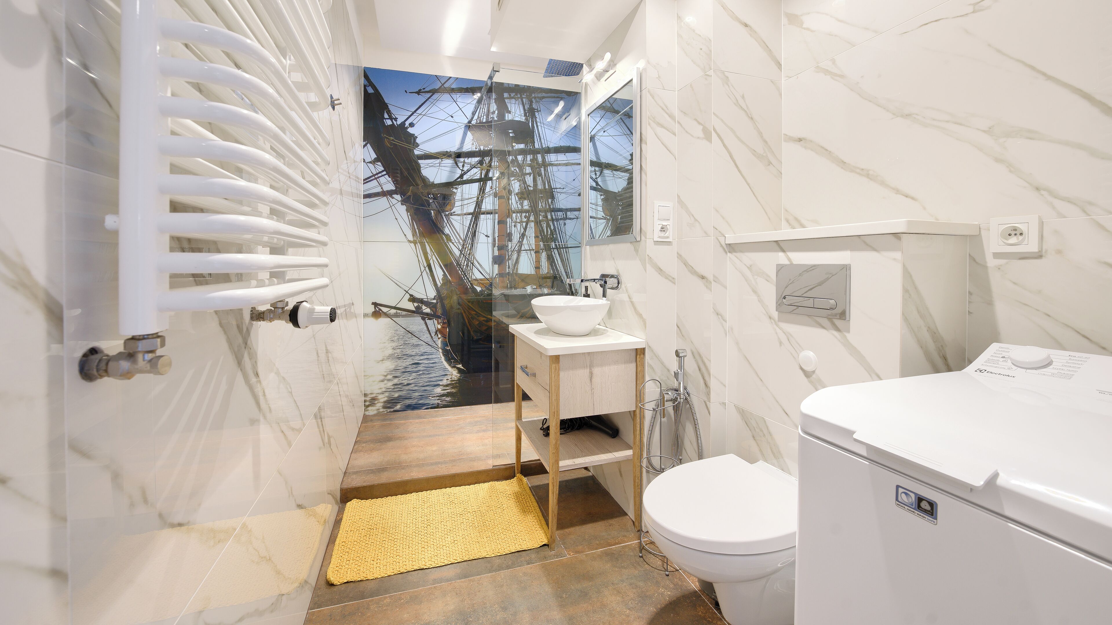 Un baño moderno con un espejo grande, un lavabo blanco y un inodoro.