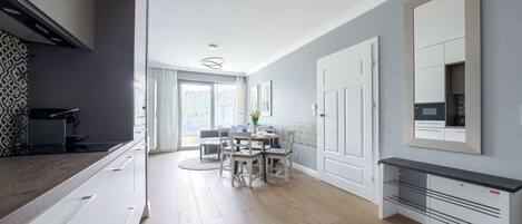 Una cocina moderna con armarios blancos, un comedor con mesa y sillas redondas, y un ventanal que proporciona luz natural.