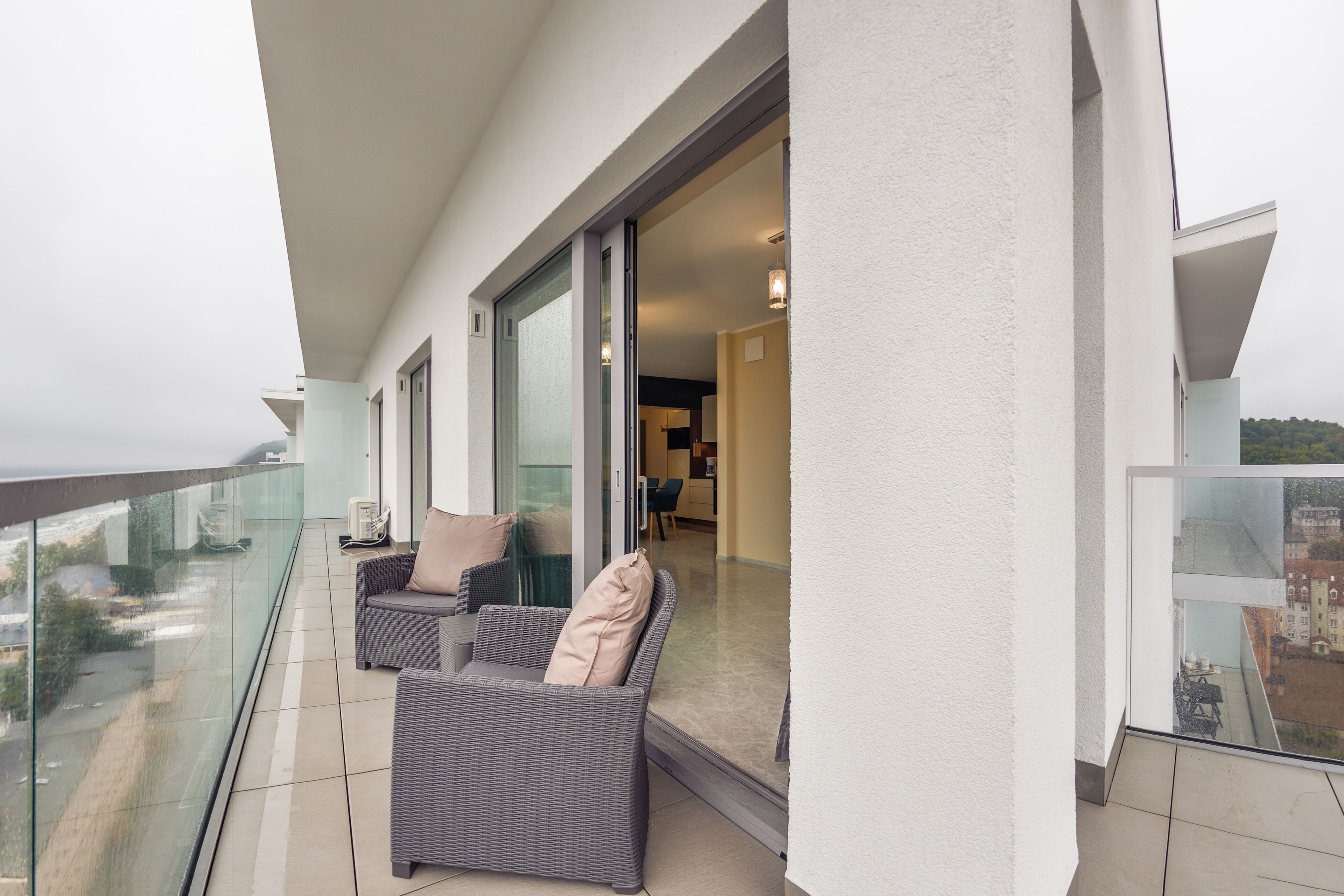 Un balcon doté de meubles en osier et d’une porte vitrée donnant sur un espace intérieur.