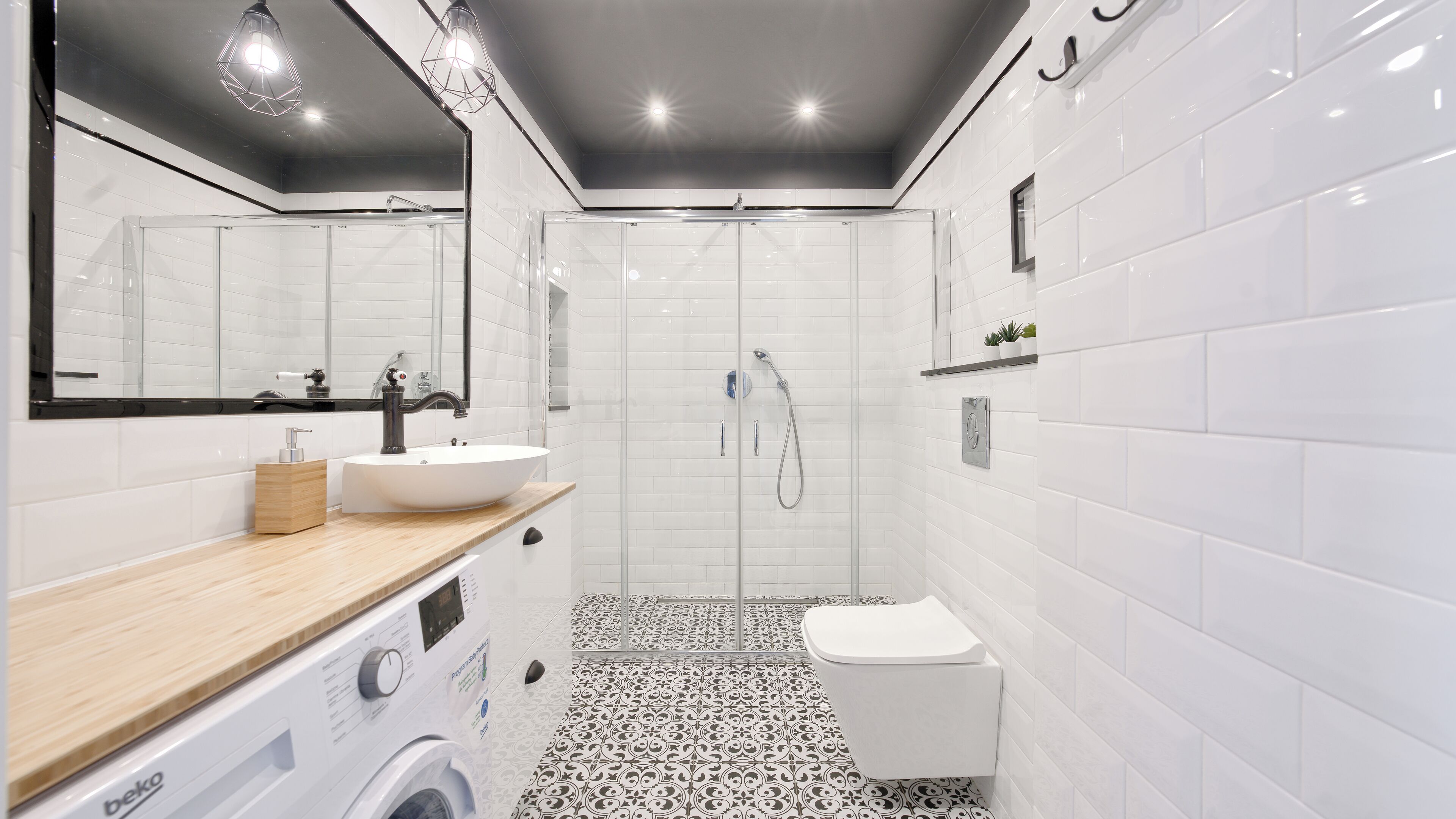A modern bathroom with a large mirror, a sink, a toilet, and a shower.