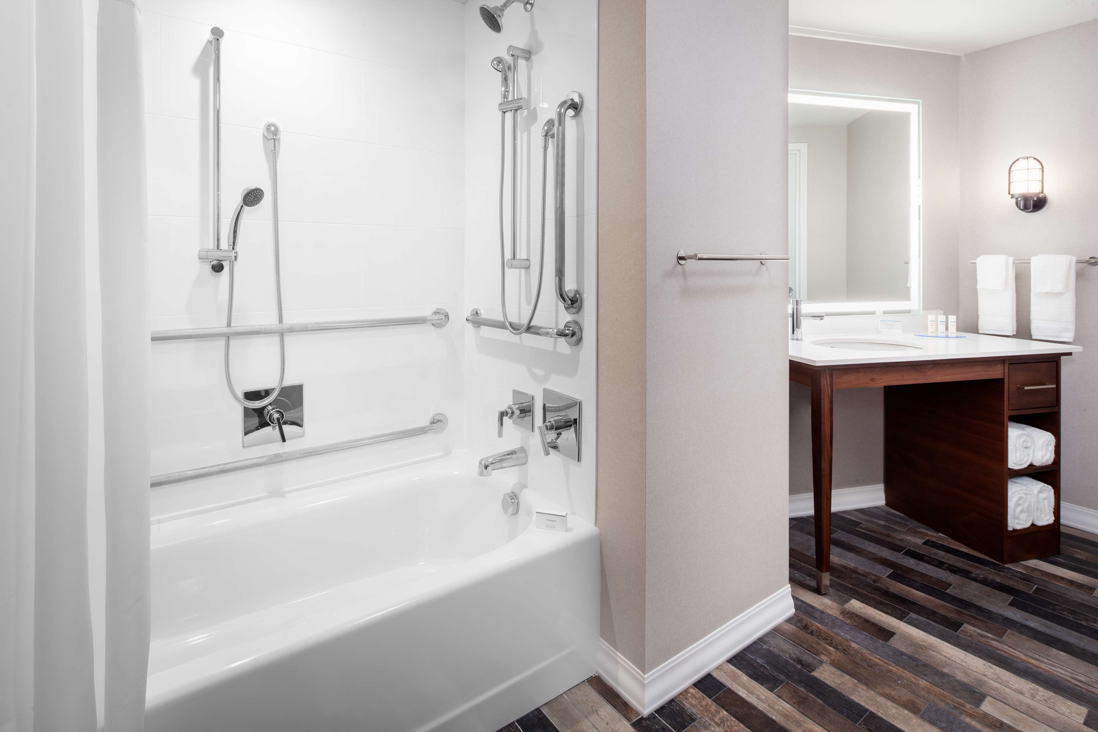 A modern bathroom with a white bathtub, shower, and vanity.