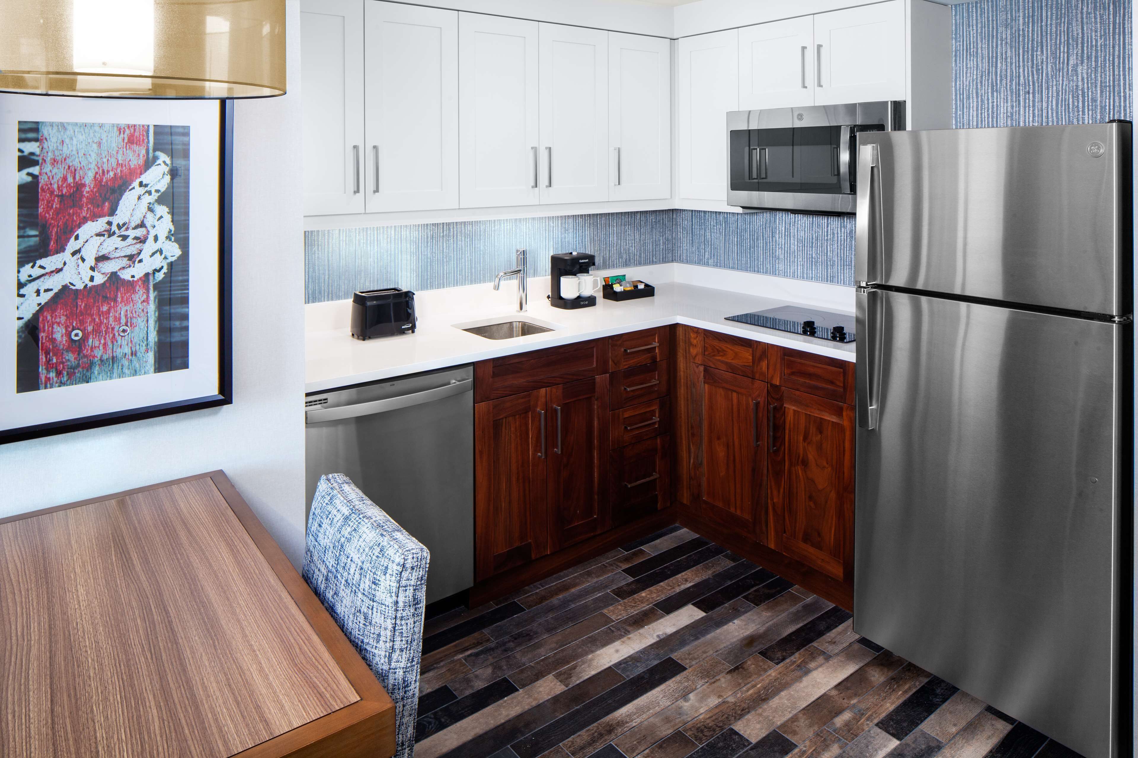 A modern kitchen with white cabinets, a stainless steel refrigerator, a microwave, and a coffee maker.