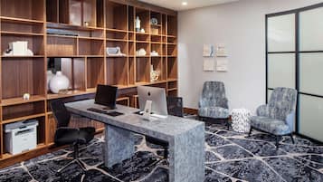 A modern office space with a marble desk, two chairs, a bookshelf, and a patterned carpet.