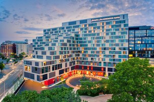 Egy modern hotel, amelyen jól látható a Hampton Inn felirata, és amely egy többemeletes épület, központi udvarral és gondozott zöldterülettel rendelkezik.