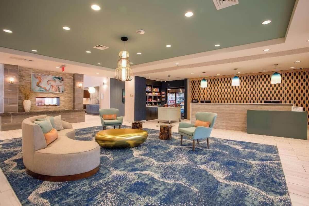 A modern lobby with a reception desk, seating area, and a large abstract painting.