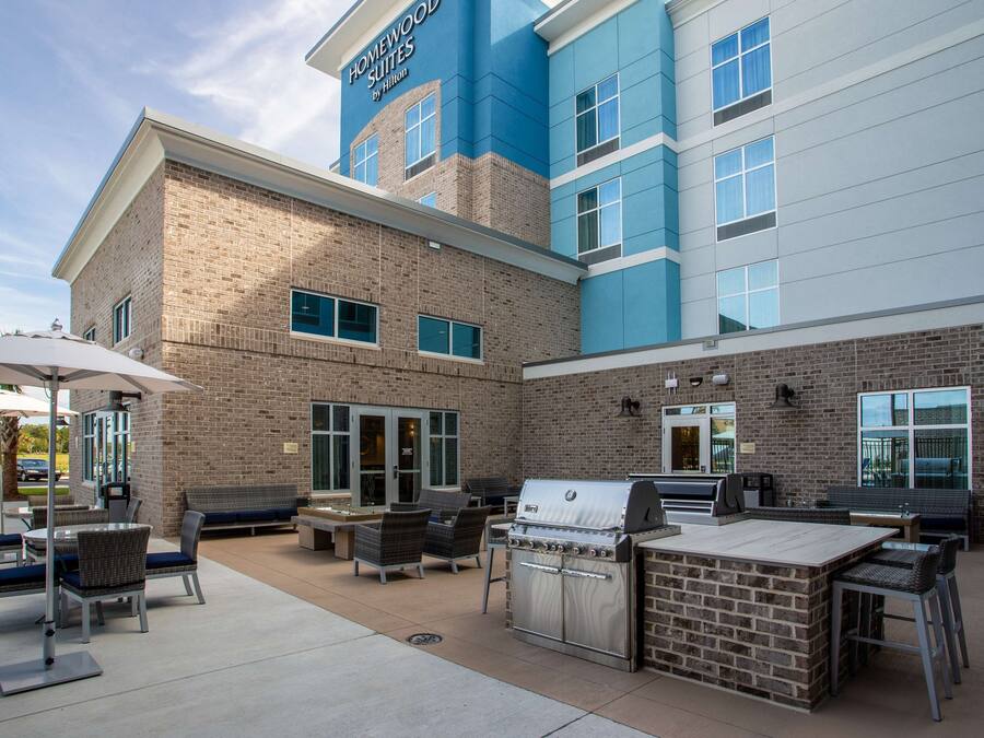 Een hotelgevel met een patio met buitenmeubilair, een barbecue en een zwembad.