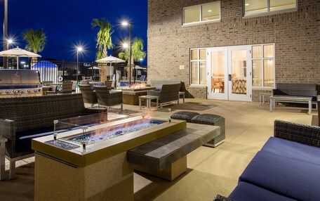 An outdoor patio area with a fire pit, seating, and a pool.