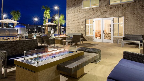 Ein Terrassenbereich im Freien mit Feuerstelle, Sitzgelegenheiten und Pool.