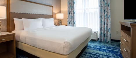 Une chambre d’hôtel avec un grand lit, une table de chevet, une télévision et une fenêtre avec des rideaux.