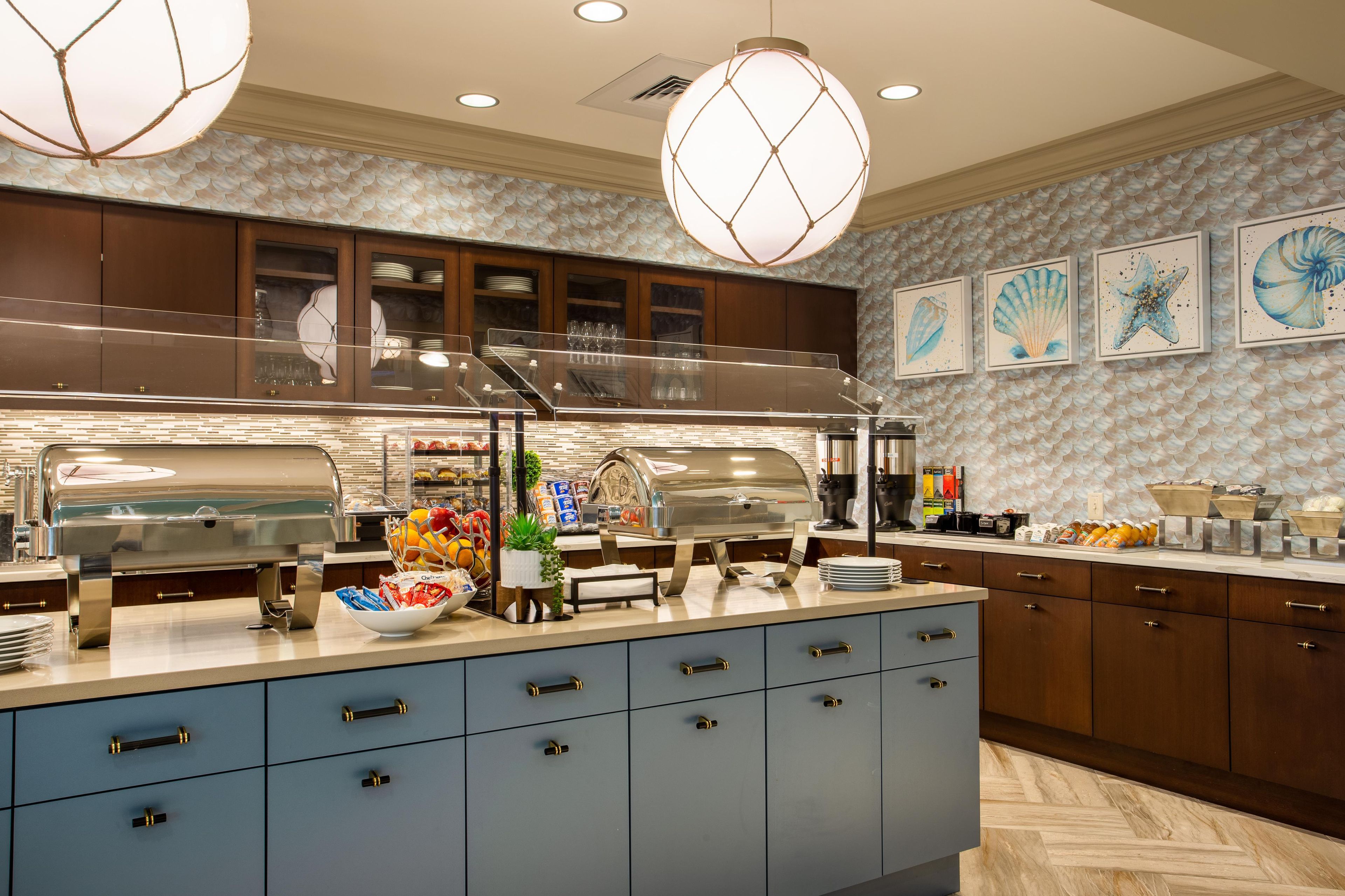 A modern kitchen with a buffet setup, wooden cabinets, and decorative wall art.