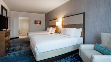 Quarto de hotel com duas camas, televisão, escrivaninha e uma cadeira.