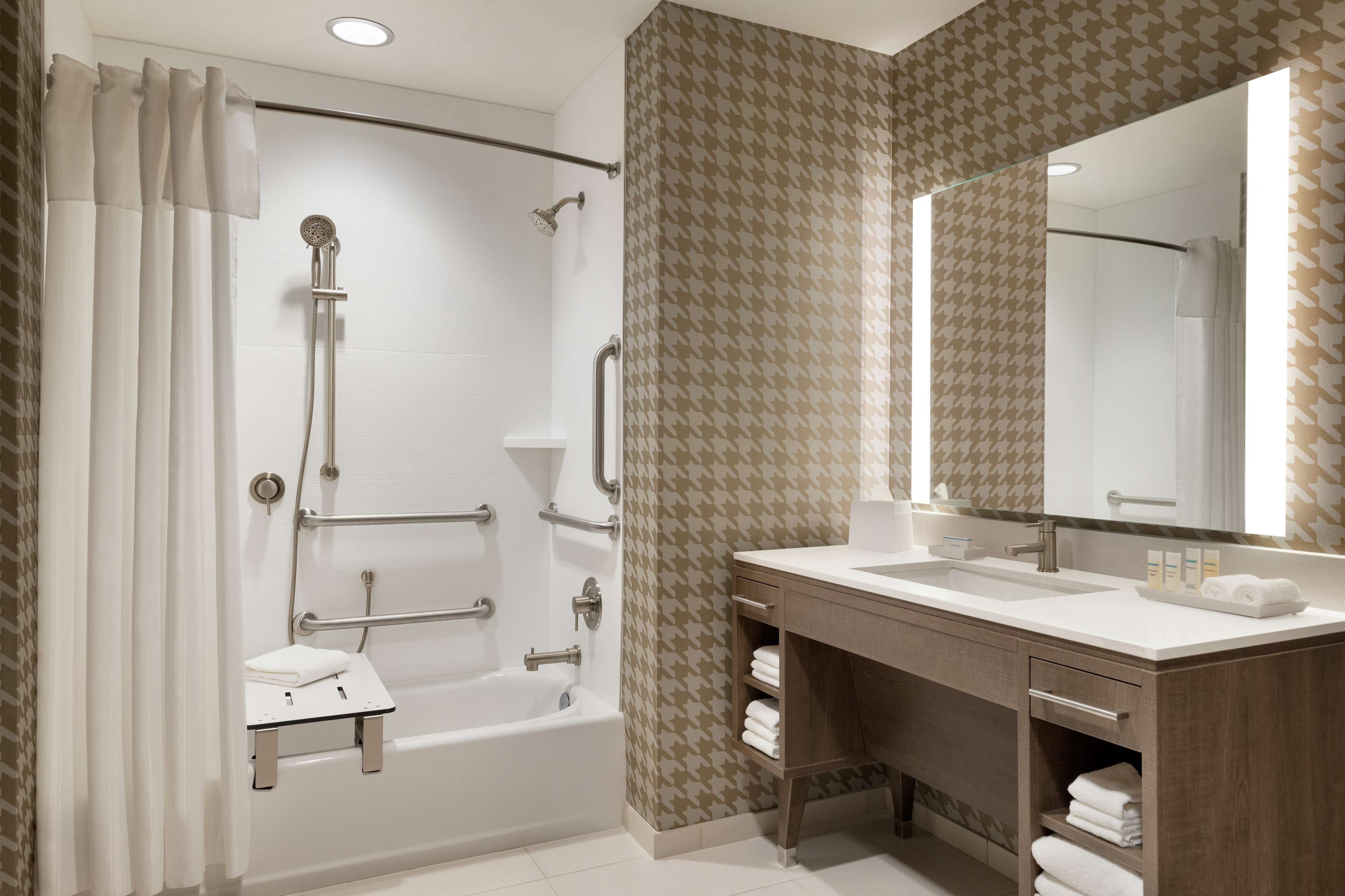Un baño moderno con ducha a ras de suelo, tocador con espejo y bañera.