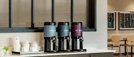 A modern kitchen with a coffee station featuring three dispensers labeled 'Regular', 'Decaf', and 'Hot Water'.