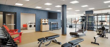 A gym with exercise equipment, benches, and a treadmill.