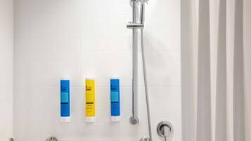 Une douche équipée d’un pommeau de douche à main, d’un distributeur de savon à main et d’un savon en barre.
