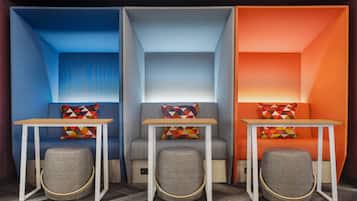 Una habitación con tres zonas de estar diferenciadas, cada una con una decoración de color distinta y una pequeña mesa.