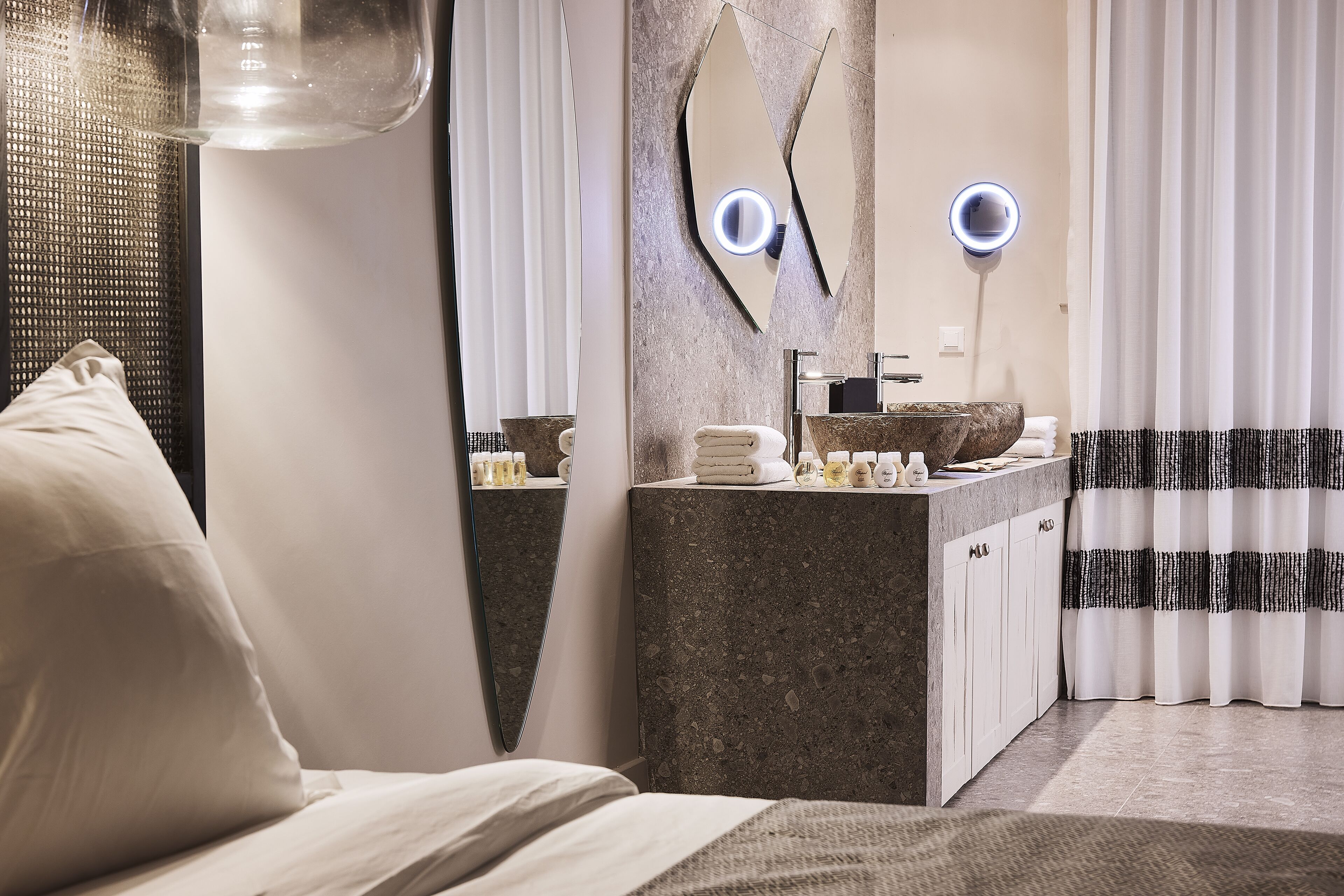 A modern bathroom with a granite countertop, a large mirror, and a towel rack.