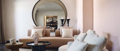 A modern living room with a beige sofa, a round coffee table, and a large mirror.