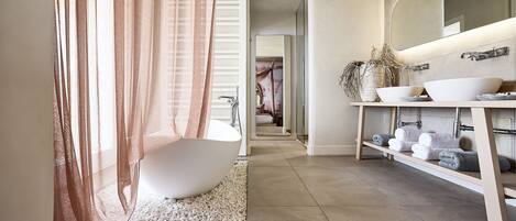 Une salle de bain moderne avec une baignoire sur pieds, un grand miroir et un meuble-lavabo doté d’étagères pour les serviettes.