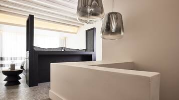 A modern interior with a minimalist design, featuring a large white console table, a dark wooden cabinet, and two hanging pendant lights.