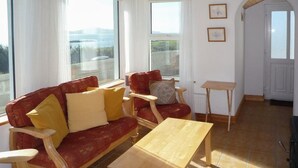 Ein Wohnzimmer mit einem roten Sofa, einem Holztisch und einem kleinen Beistelltisch.
