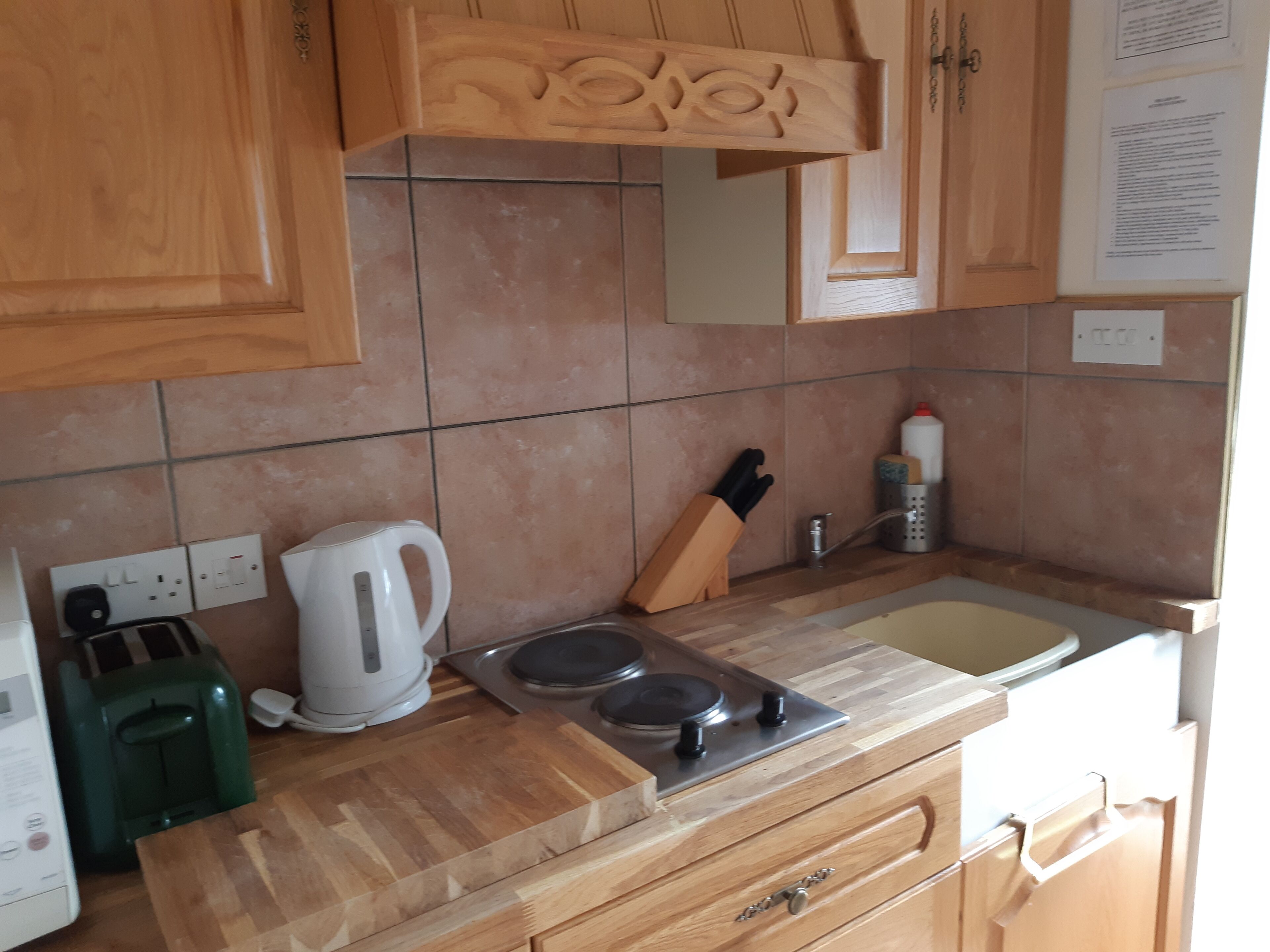 A kitchen with wooden cabinets, a gas stove, a kettle, and a toaster.