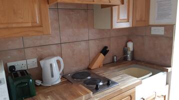 A kitchen with wooden cabinets, a gas stove, a kettle, and a toaster.