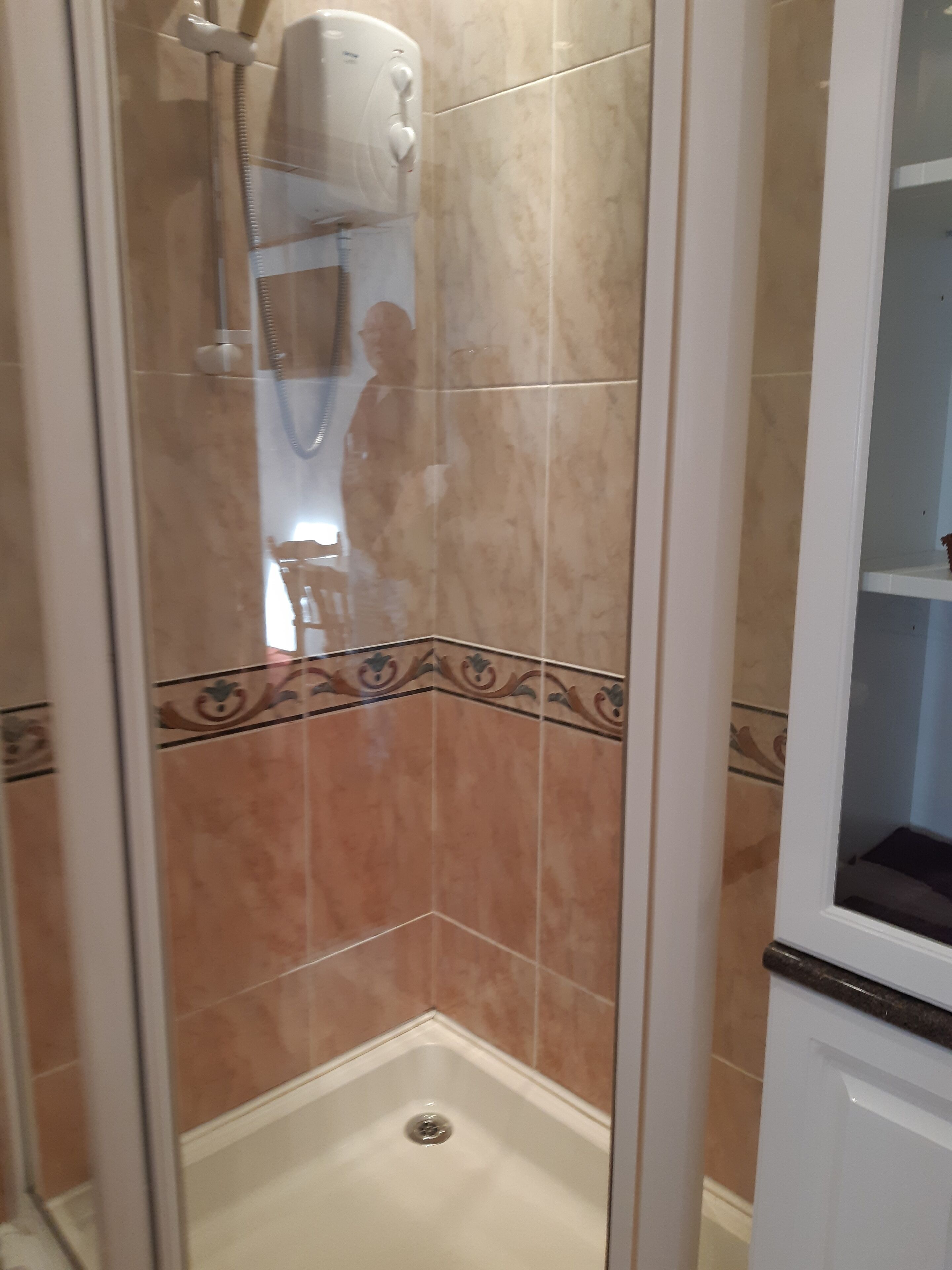 Ein Eckbereich eines Badezimmers mit Duschkabine, Toilette und Waschbecken.