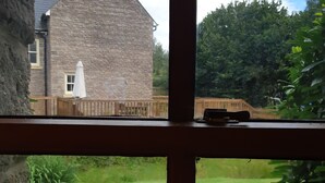 Un bâtiment en pierre, doté d’un toit en pente et d’une clôture en bois en arrière-plan.