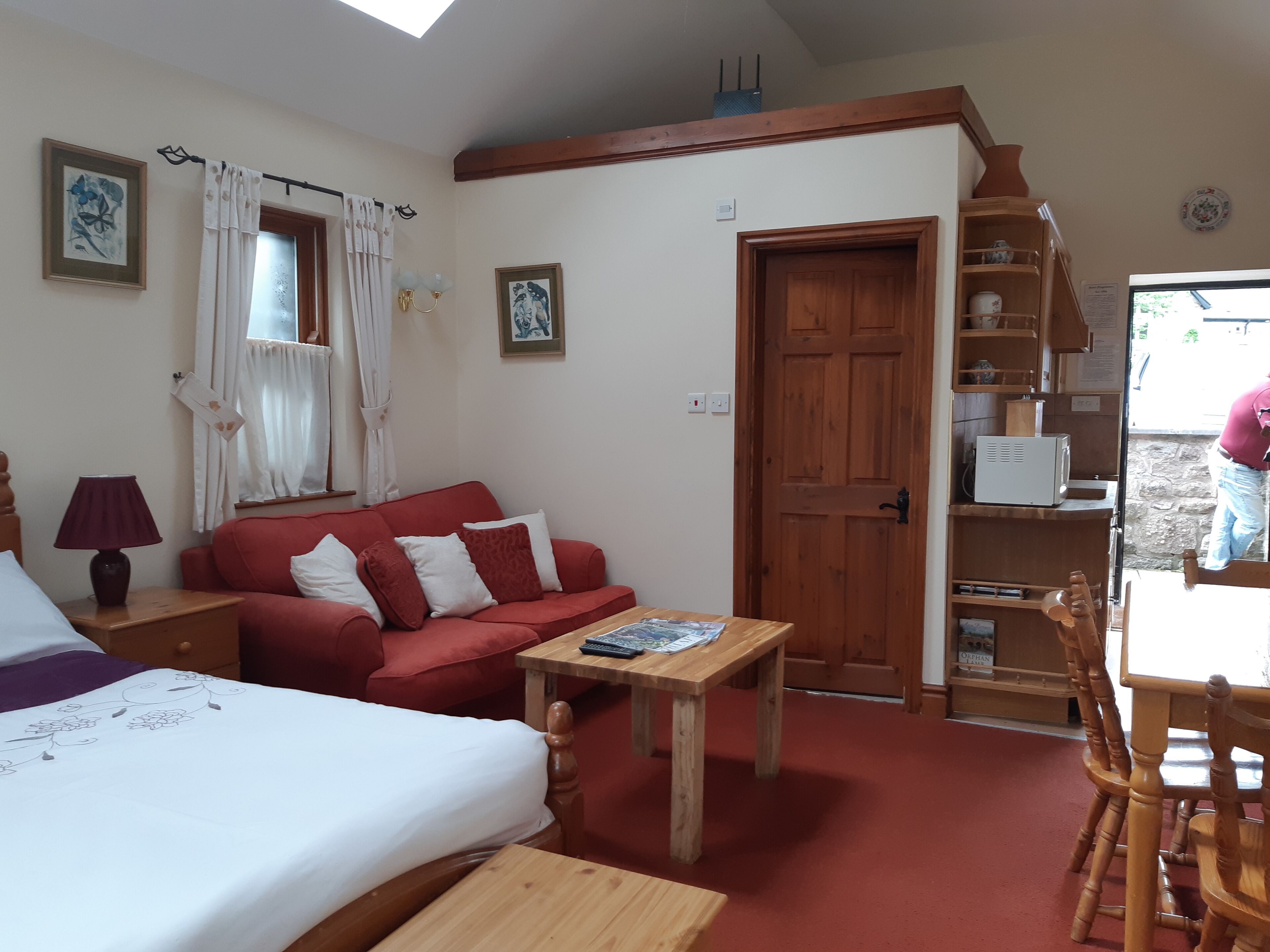Ein gemütliches Zimmer mit einem Bett, einem roten Sofa, einem Holztisch und einem Holzstuhl.