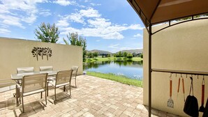 Une terrasse avec une table et des chaises, un mur décoratif, un bassin et, au loin, un terrain de golf.