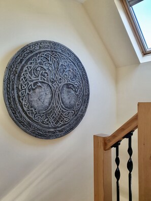 A circular wall decoration with intricate patterns, a wooden staircase with black balusters, and a skylight above. - Retreat in charming Pitlochry! (Pitlochry)