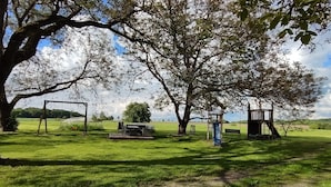 A park with a picnic table, a swing set, and a playground structure.