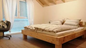A bedroom with a wooden bed, a chair, and a window with blinds.