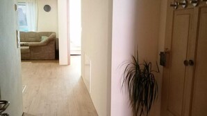 A staircase leading to a wooden door, a potted plant, and a living room with a sofa and curtains.