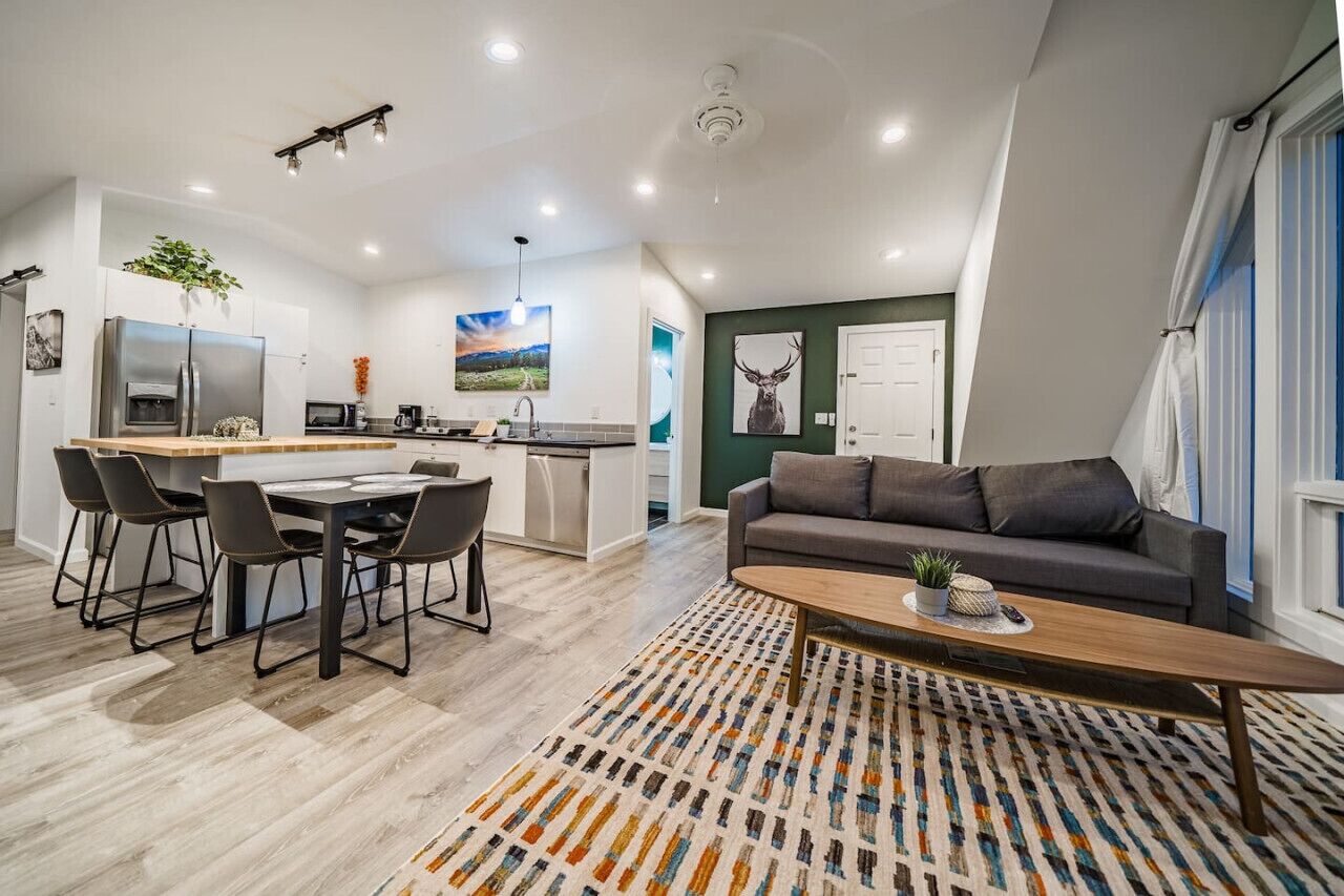 Una cocina moderna con zona de comedor, un sofá gris y un tapete estampado.