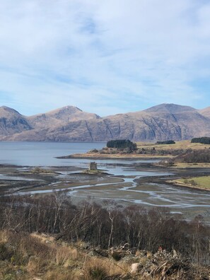 A landscape with a body of water, hills, and a small tower-like structure.