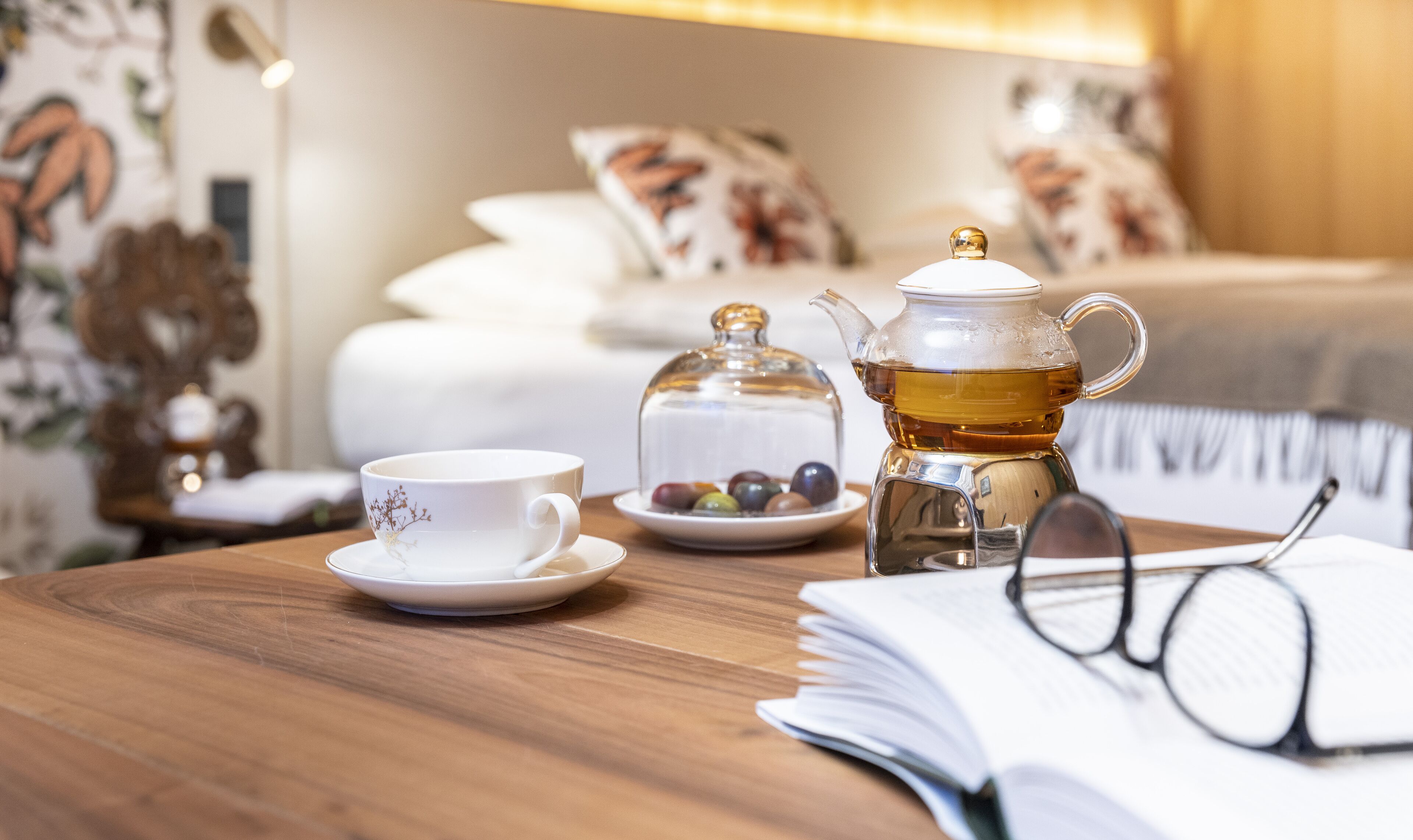 A wooden table with a teapot, a cup, and a plate of colorful objects.