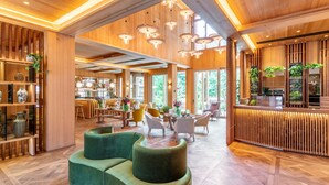 Eine geräumige Lobby mit Holzboden, grünen Polstersitzmöglichkeiten und einer Bar mit Pflanzen.