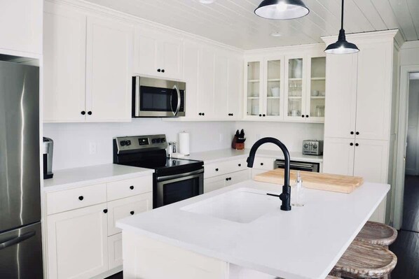 Una cocina moderna con armarios blancos, electrodomésticos de acero inoxidable y una isla central con fregadero.