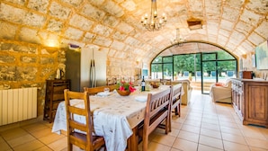 A stone-walled dining area with a table set for two, a chandelier, and a view of the outdoors. - Finca Sa Mina for 12 with pool in Mallorca (Selva)