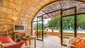 A cozy room with a stone wall, a TV, a wooden table, and a sofa. - Finca Sa Mina for 12 with pool in Mallorca (Selva)