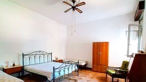 Une chambre à coucher comprenant un lit, une armoire, une chaise, un bureau et un ventilateur de plafond.