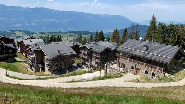 A cluster of wooden buildings with balconies, set against a backdrop of mountains and clear skies. - F204 - 46 m2 -  2P+Cab - 4/6 pers (Prapoutel)