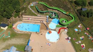 An aerial view of a water park with multiple slides, a swimming pool, and a sandy area with umbrellas. - F204 - 46 m2 -  2P+Cab - 4/6 pers (Prapoutel)